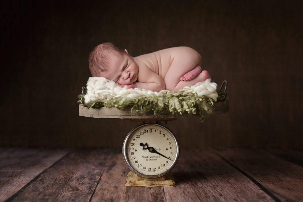 Baby boy on scale for newborn portraits.